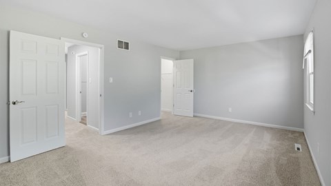 A spacious room with white doors and carpeted floor.