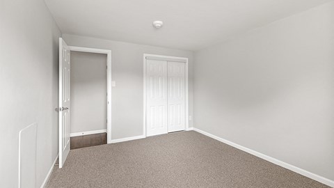 a bedroom with white walls and carpet and two doors