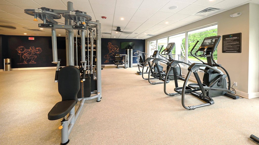 a gym with various cardio equipment in a room with windows