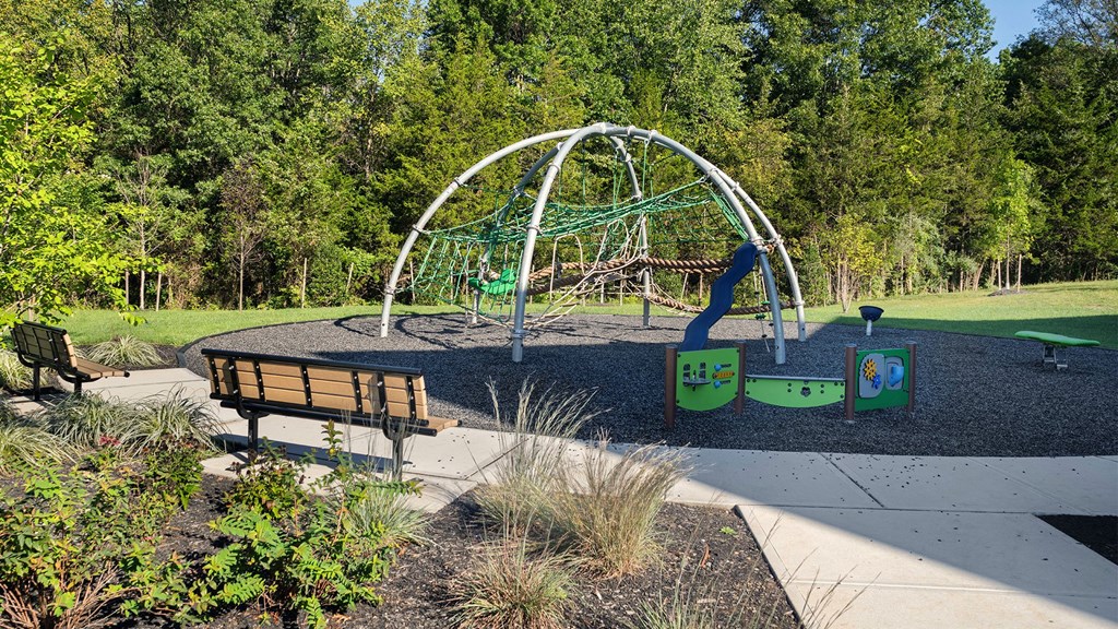 a swing set in a park with benches and trees