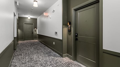 A hallway with a carpeted floor and a door on the right.