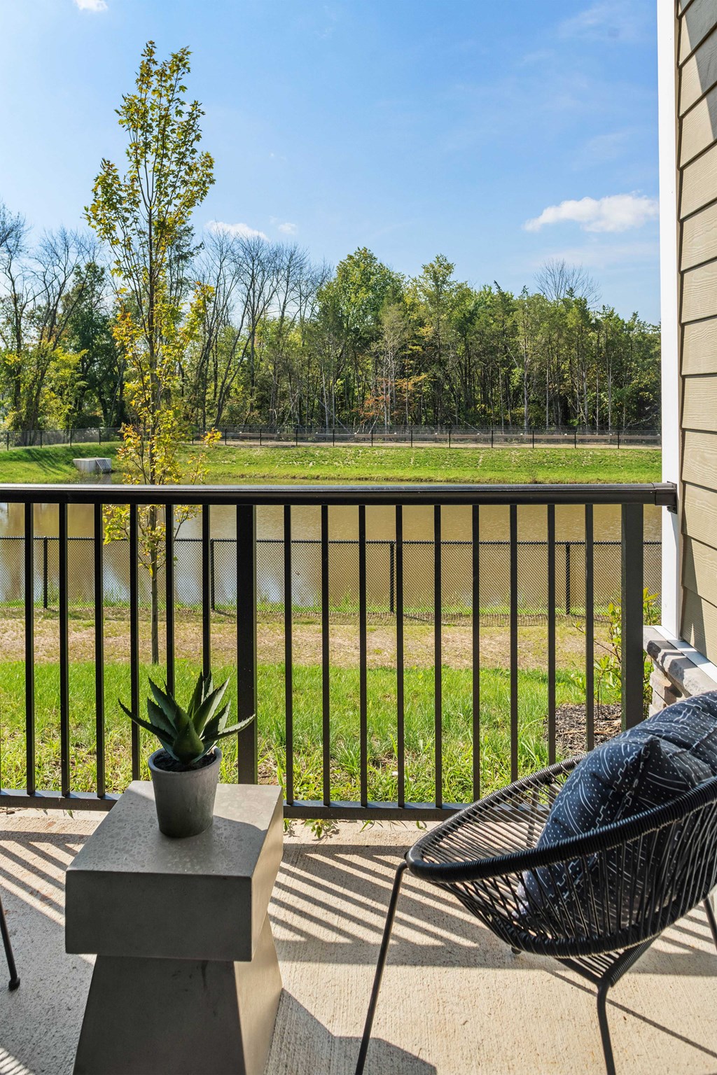 a patio with a chair and a potted plant overlooking a field