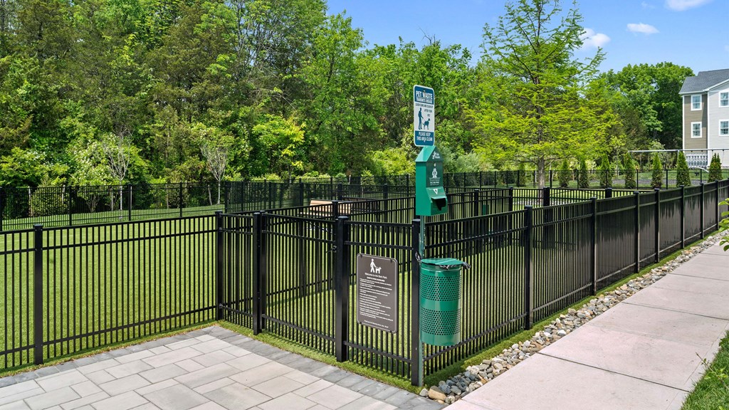 a park with a fence and a green trash can