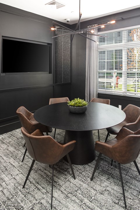 a conference room with a round table and chairs and a television