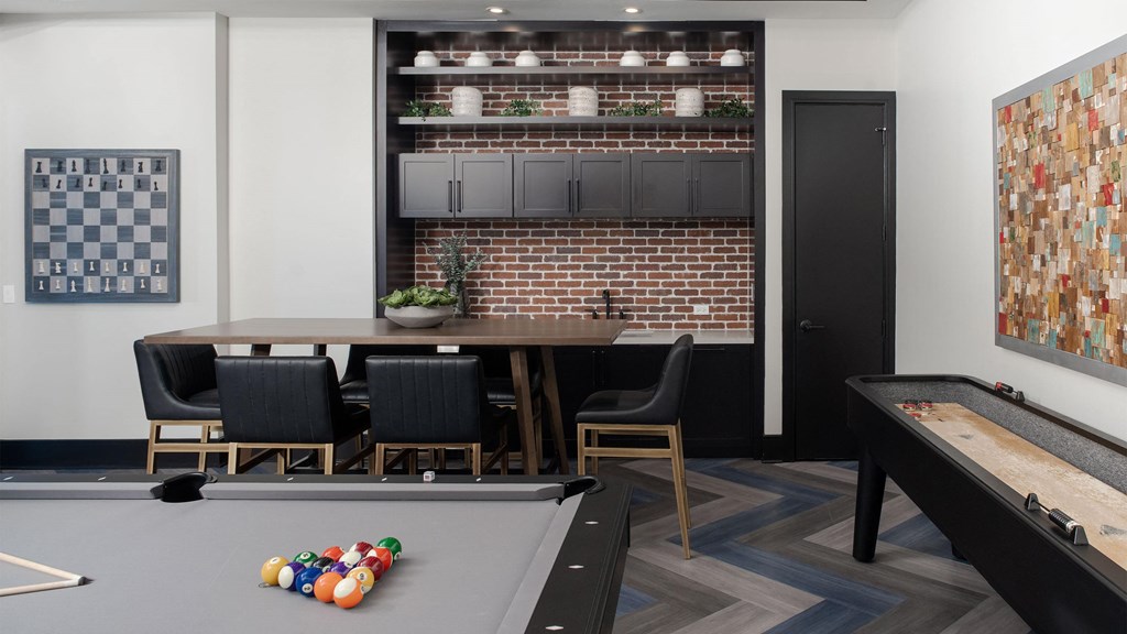 a communal area with a pool table and a bar and a game table with chairs