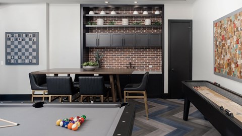 a communal area with a pool table and a bar and a game table with chairs