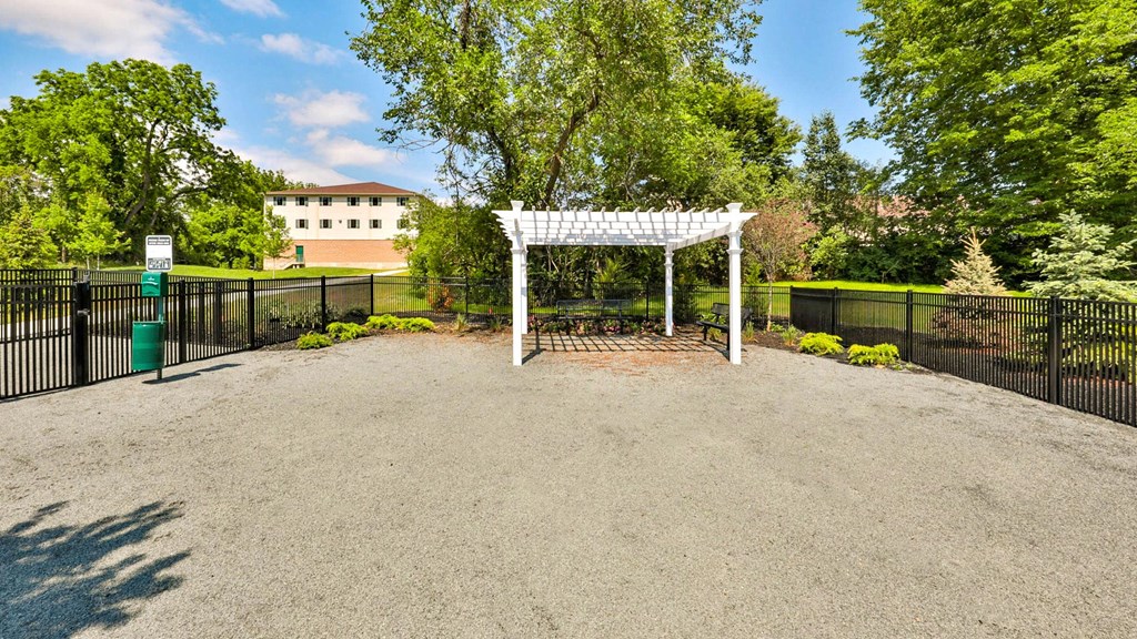 a white gazebo in a park with trees and a fence