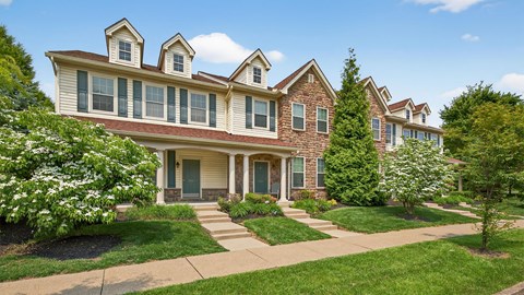 A large house with a front porch and a green lawn.