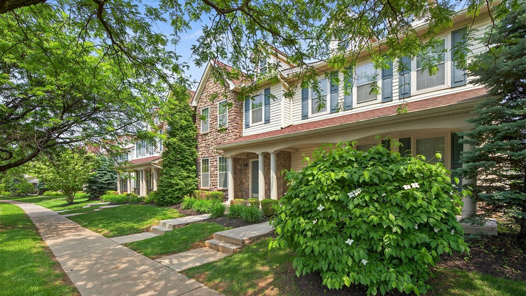 A house with a green lawn and a tree in front.