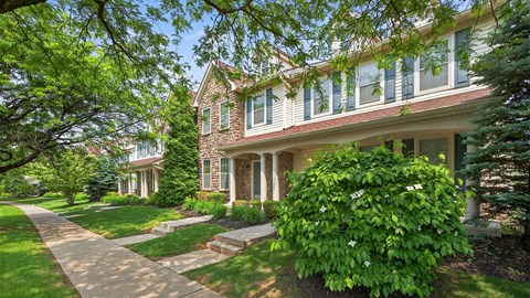 A house with a green lawn and a tree in front.