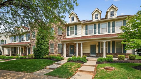 A house with a green lawn and a tree in front.