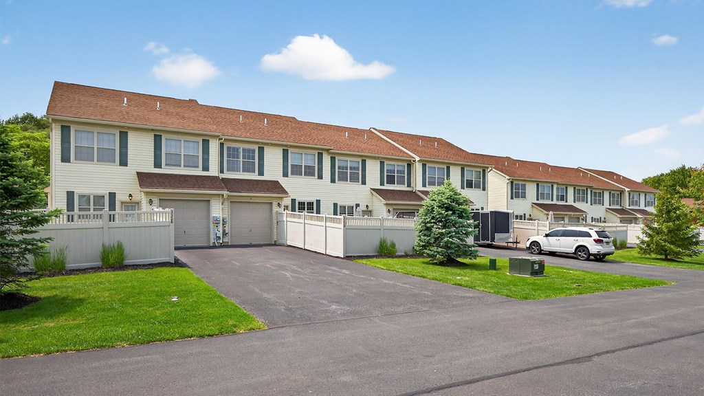 A white building with brown roofs and a car parked in front.