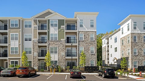 an image of an apartment building with cars in a parking lot