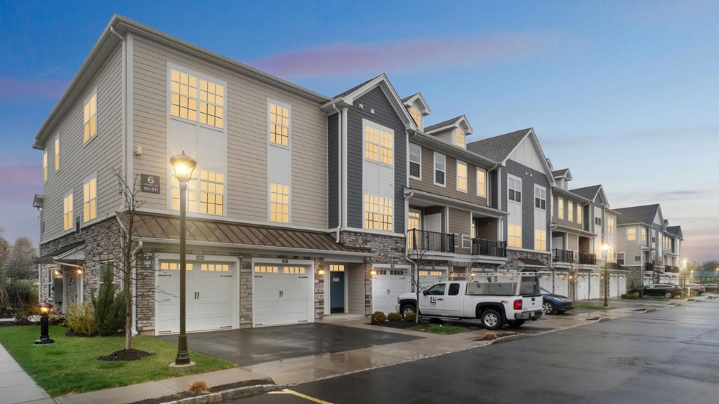A row of townhouses with garages and parked cars.