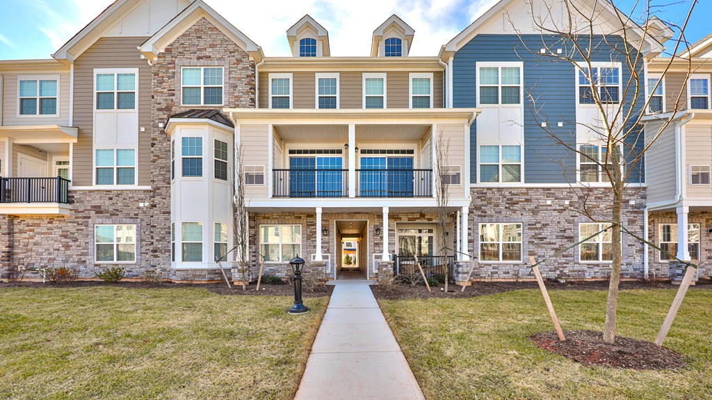 an exterior view of an apartment building with a sidewalk in front of it