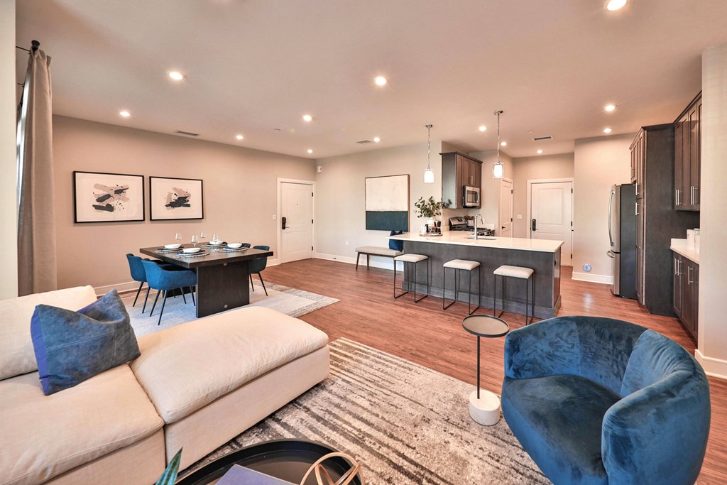 a living room and kitchen with a couch and chairs