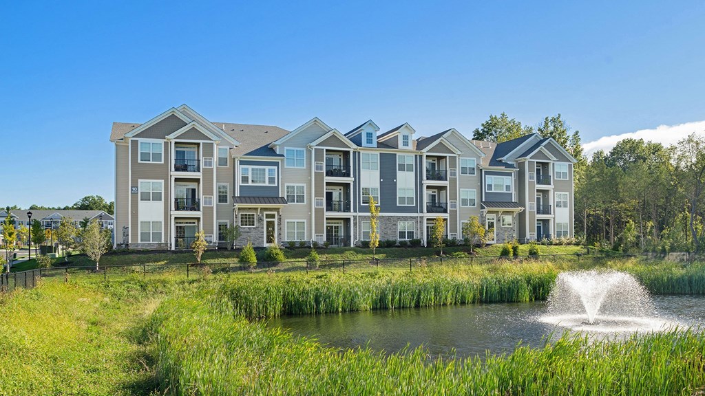 a pond with a fountain in front of an apartment building