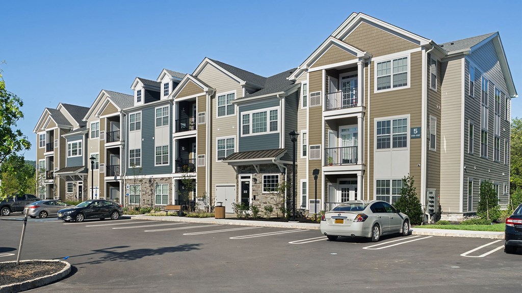 a row of apartment buildings with cars parked in a parking lot