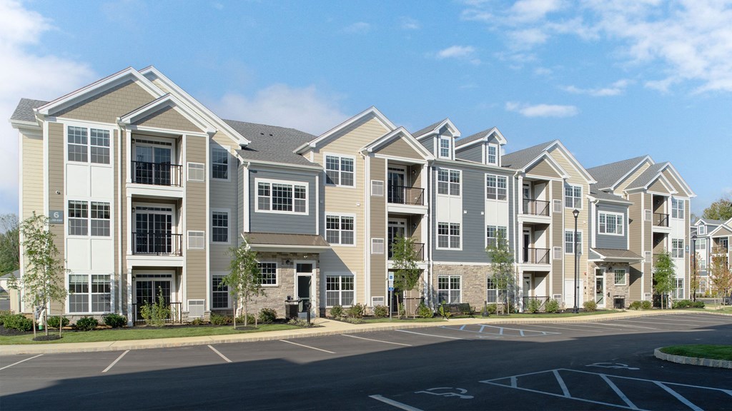 a row of apartment buildings on a street with a parking lot