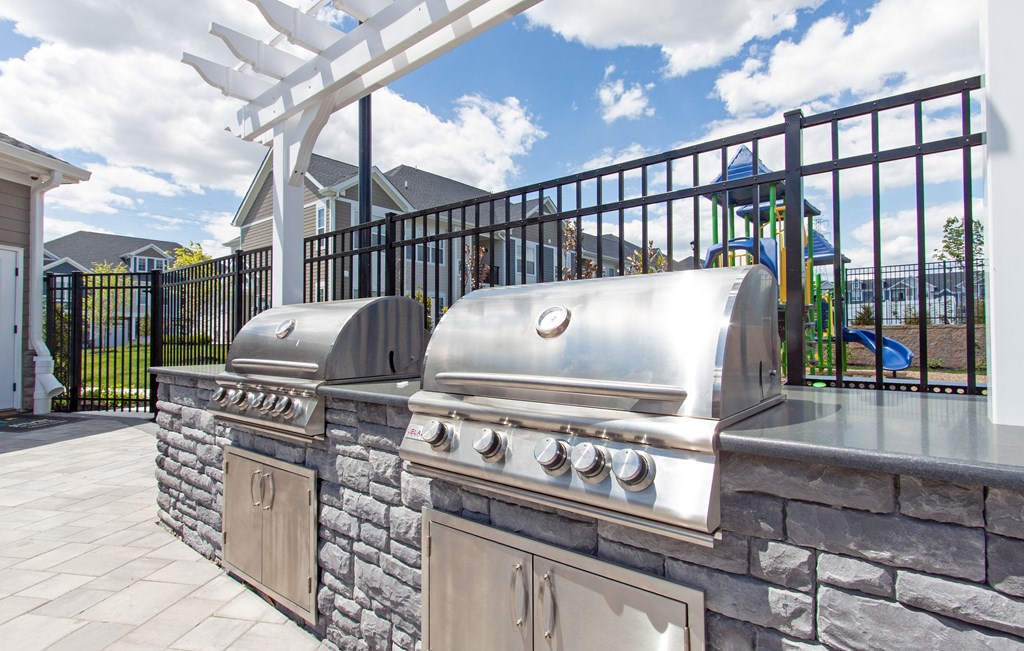 an outdoor kitchen with a grill and a swing set