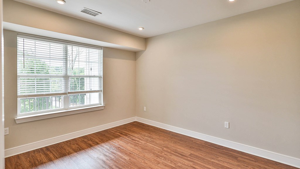 an empty living room with wood floors and a large window
