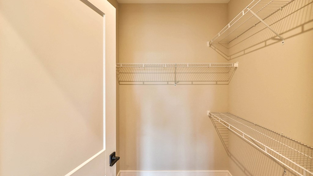 an empty closet with two shelves and a door open to a hallway with a closet