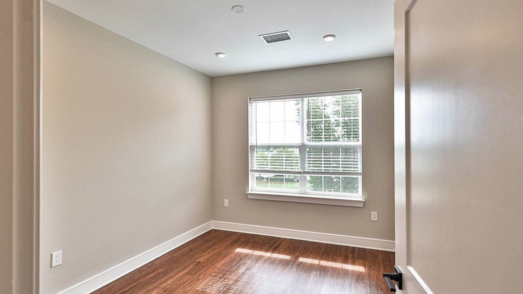 an empty room with wood floors and a window
