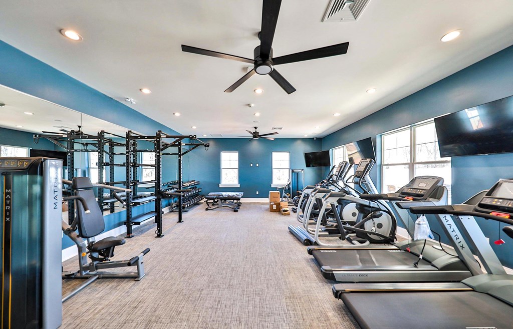 spacious gym with cardio equipment and windows at the estates apartments