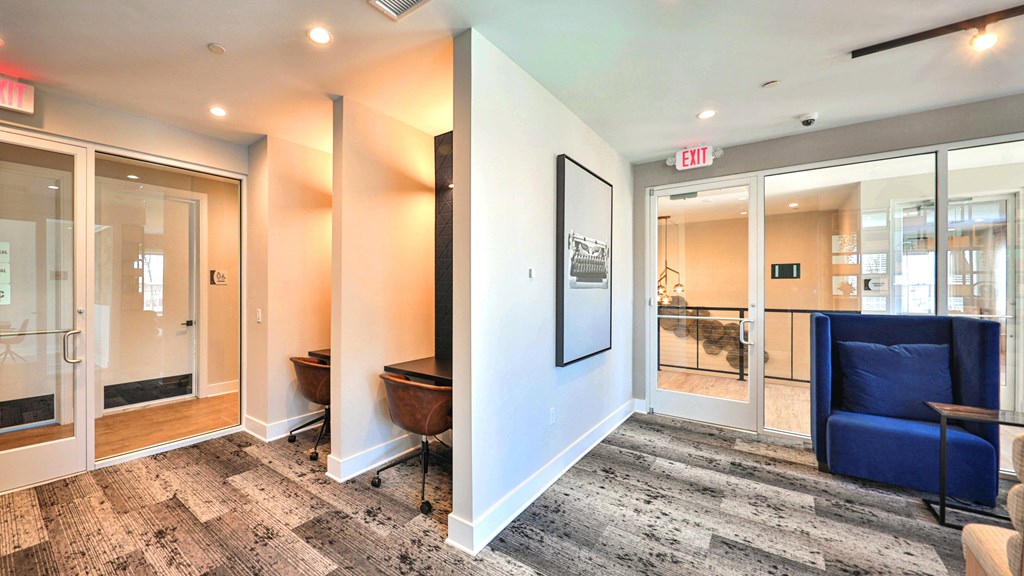 a corridor with glass doors and a lobby with blue chairs