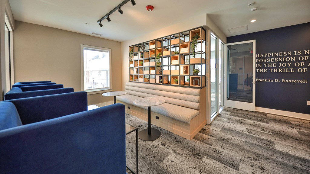 a lounge area with blue chairs and a wall with a quote on it