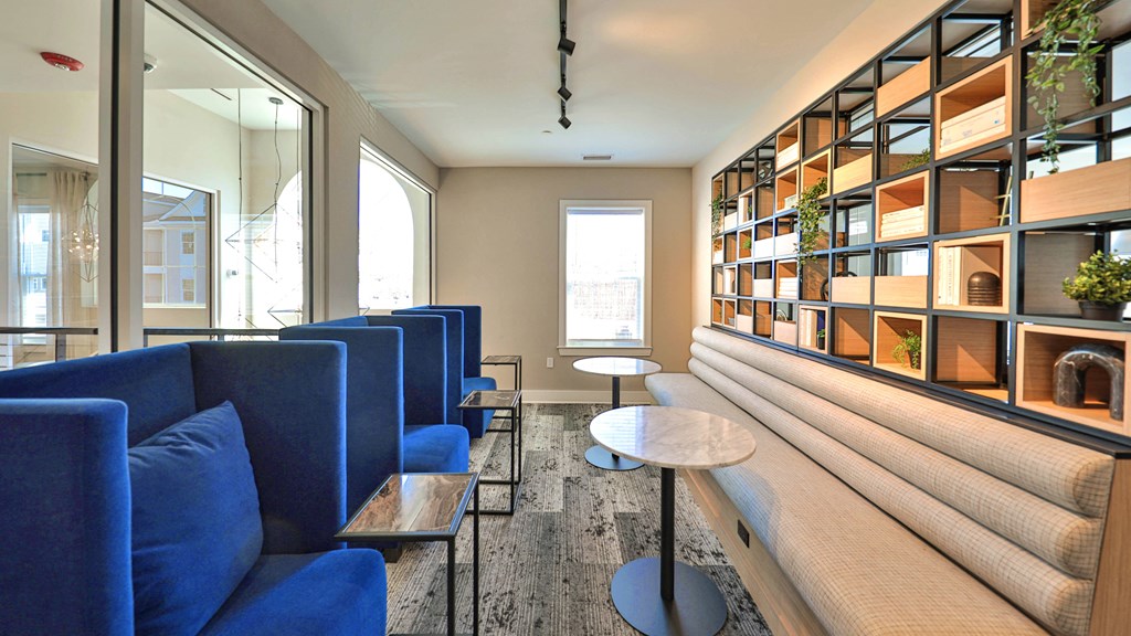 a lounge area with blue couches and tables and a wooden bench