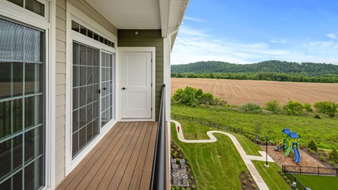 A view from a balcony overlooking a playground and a field.