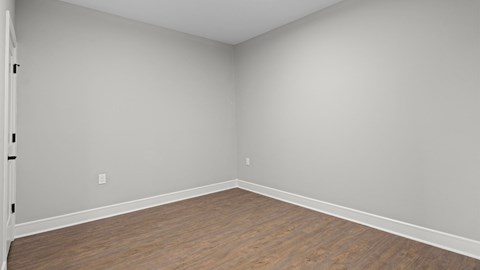 A room with wooden flooring and white walls.