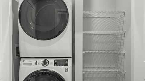 A black and white photo of a washing machine and dryer with the dryer door open.