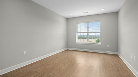 A room with wooden flooring and a window overlooking a landscape.