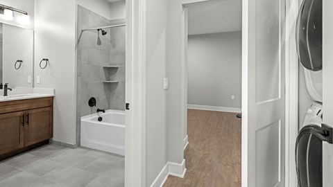 A modern bathroom with a walk-in shower and a washer and dryer.