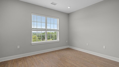 A room with a large window and wooden flooring.