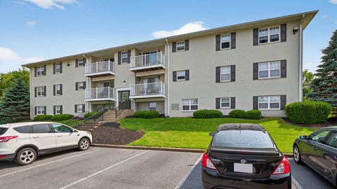 A white car is parked in front of a black car in a parking lot.