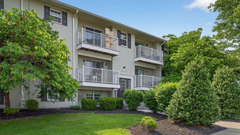 A building with a balcony and a green lawn in front.