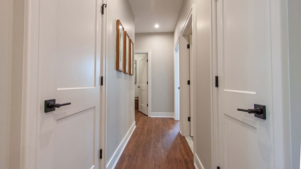 a hallway with white walls and wooden floors and white doors