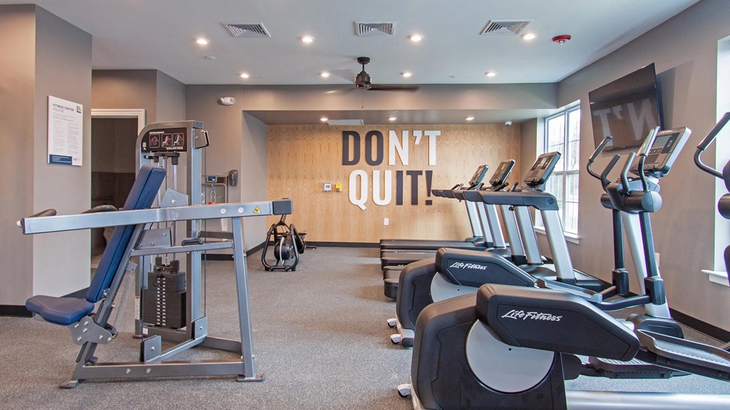 a gym with cardio equipment and a dont quit sign on the wall