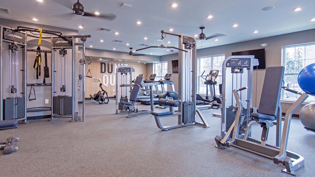 a gym with weights and cardio equipment in a building with windows