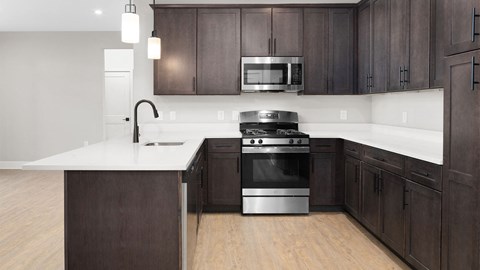 A modern kitchen with dark wood cabinets and stainless steel appliances.