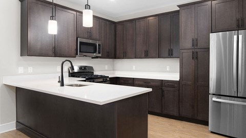 A modern kitchen with dark brown cabinets and a white countertop.