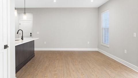 A room with a wooden floor and a window with blinds.