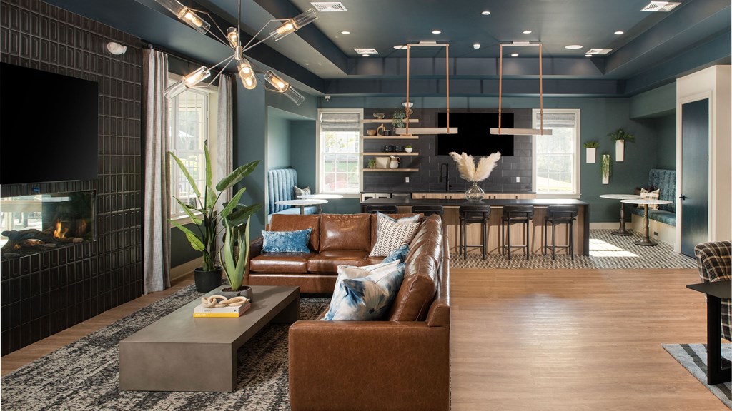 a living room and kitchen with blue walls and leather furniture
