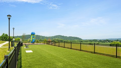 A playground with a blue slide is surrounded by a black fence.