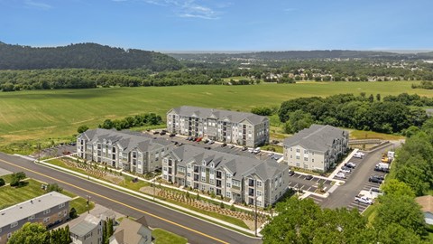 A large apartment complex is situated on a hill with a road in front of it.