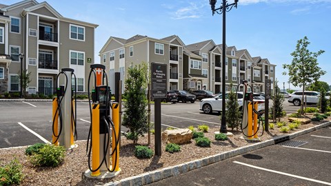 A row of yellow gas pumps in front of apartment buildings.