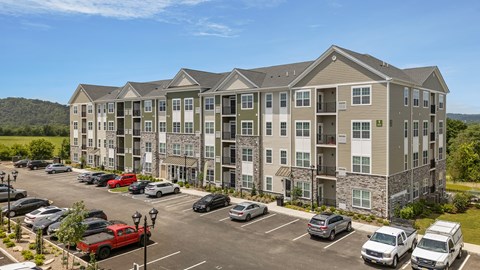 A large apartment complex with a parking lot in front.
